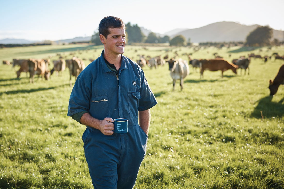 Male farmer with coffee mug on farm with dairy cows